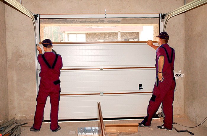 kırmızı tulumlu işçiler garaj kapısı montajı yapıyor